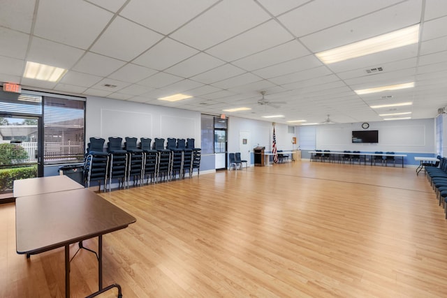 gym featuring a paneled ceiling, ceiling fan, and light hardwood / wood-style floors