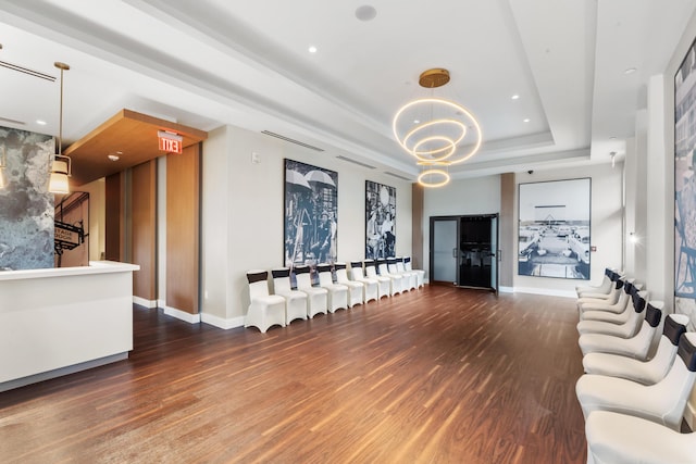 unfurnished living room featuring a raised ceiling, dark hardwood / wood-style flooring, and a chandelier