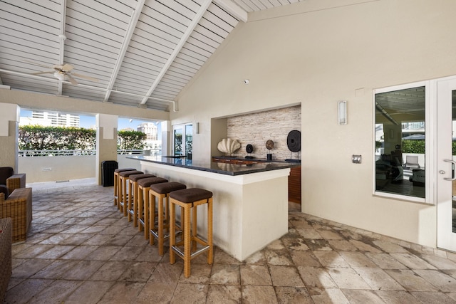 bar with beamed ceiling, plenty of natural light, ceiling fan, and high vaulted ceiling