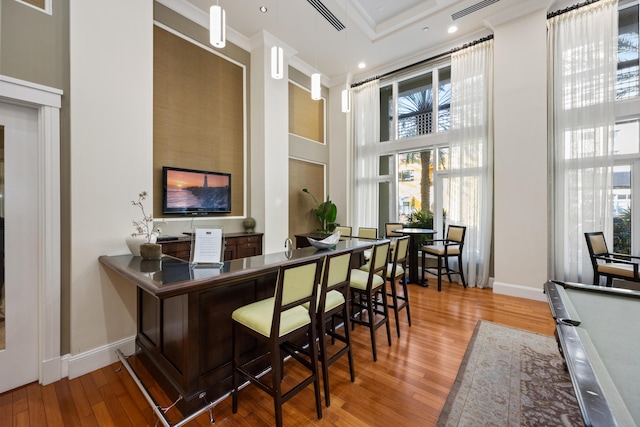 bar featuring hardwood / wood-style floors, a healthy amount of sunlight, and a towering ceiling