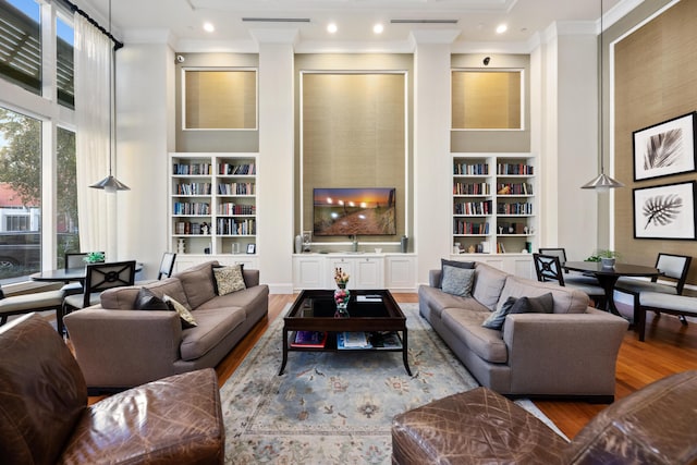 living room featuring wood-type flooring, built in features, and crown molding