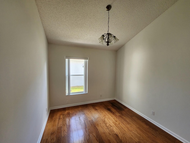 unfurnished room featuring wood-type flooring, a textured ceiling, and a notable chandelier