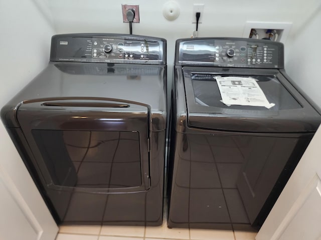 clothes washing area featuring light tile patterned floors and washing machine and clothes dryer