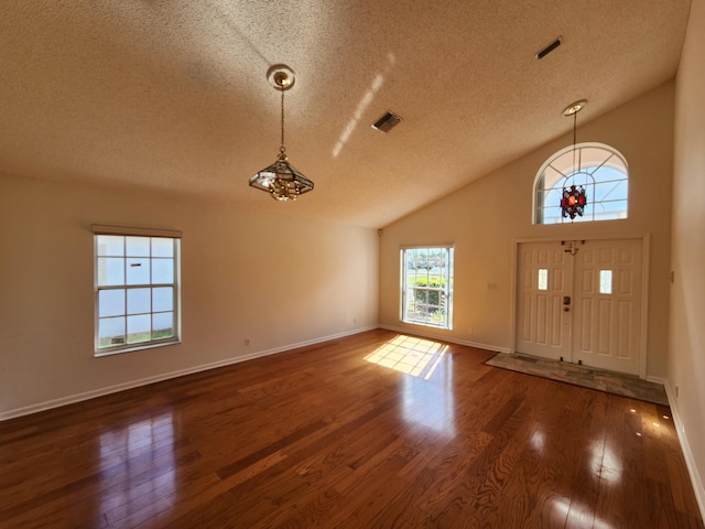 foyer entrance featuring lofted ceiling, dark hardwood / wood-style flooring, and a textured ceiling