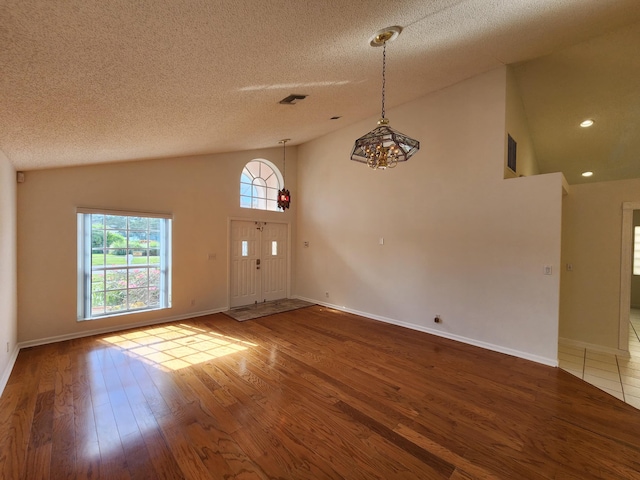 entryway with wood-type flooring, a textured ceiling, and high vaulted ceiling