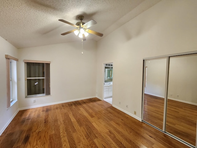 unfurnished room featuring hardwood / wood-style floors, ceiling fan, a textured ceiling, and vaulted ceiling