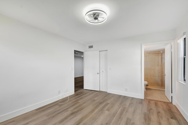 unfurnished bedroom with light hardwood / wood-style floors, ensuite bath, and a closet