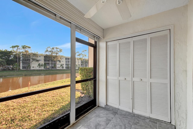 unfurnished sunroom with ceiling fan and a water view