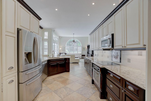 kitchen with dark brown cabinetry, sink, light stone counters, decorative backsplash, and appliances with stainless steel finishes