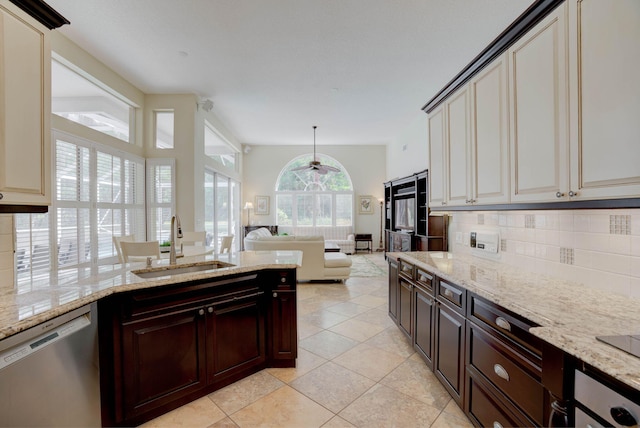 kitchen featuring sink, stainless steel dishwasher, light stone countertops, tasteful backsplash, and light tile patterned flooring