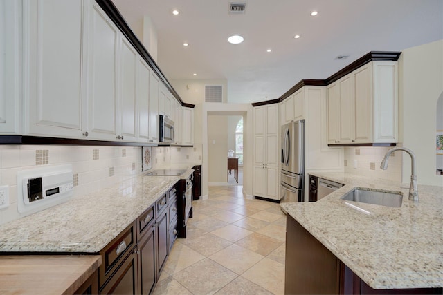 kitchen with white cabinetry, light stone countertops, sink, and stainless steel appliances