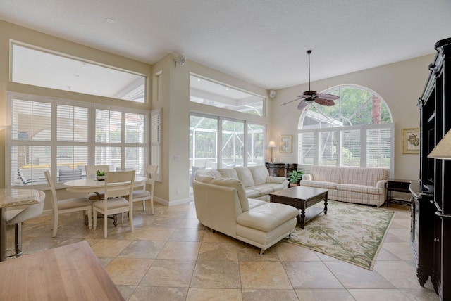 living room featuring ceiling fan, light tile patterned flooring, and a textured ceiling