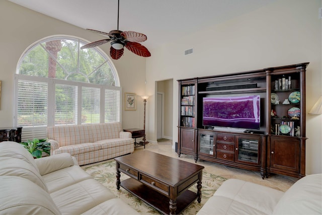 living room with ceiling fan, a towering ceiling, and light tile patterned floors