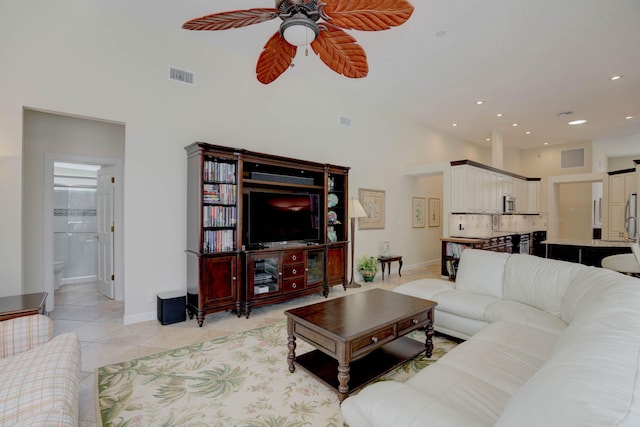 living room with ceiling fan, light tile patterned flooring, and a towering ceiling