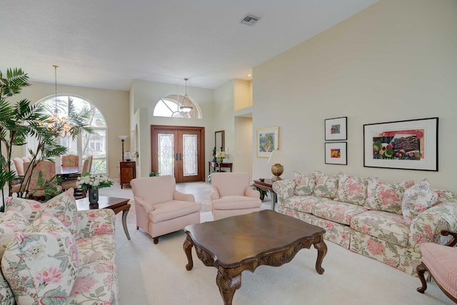 living room featuring light carpet, french doors, and a high ceiling