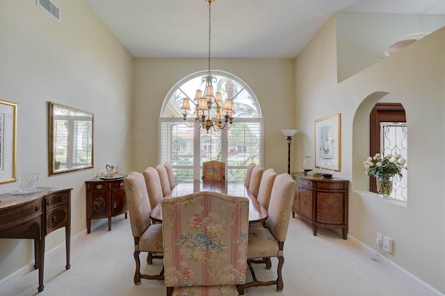 carpeted dining area with an inviting chandelier