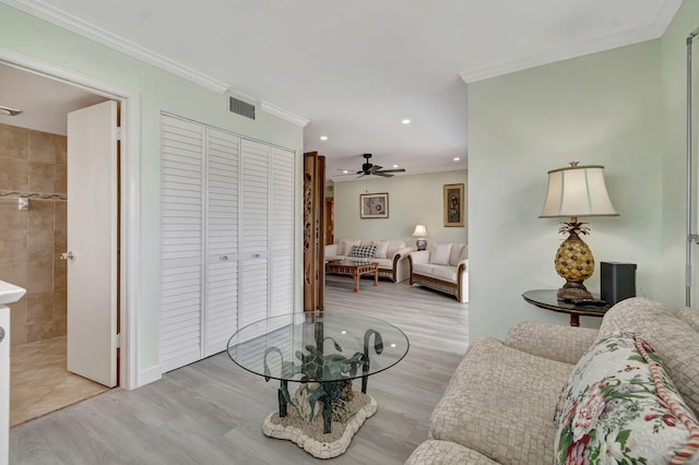 living room with light wood-type flooring, ceiling fan, and crown molding