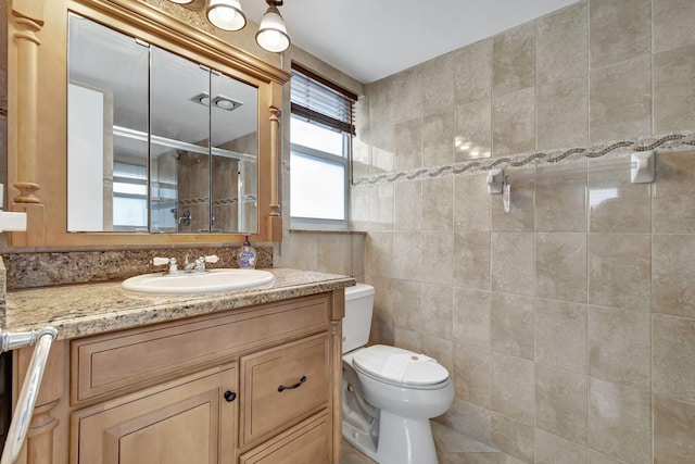 bathroom with vanity, tile patterned flooring, toilet, tile walls, and an enclosed shower