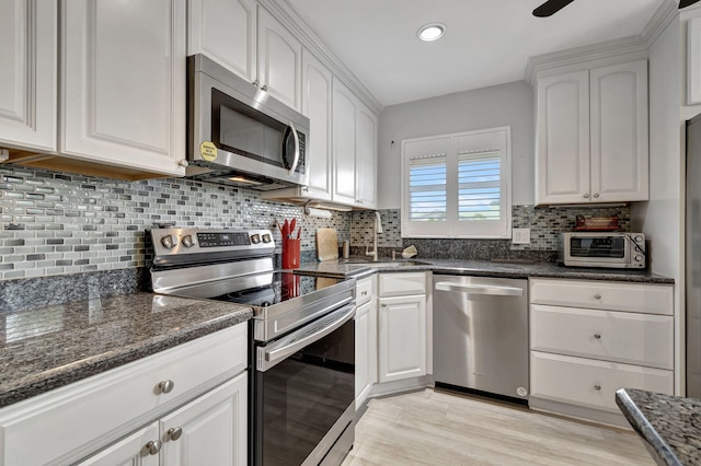 kitchen featuring white cabinets, sink, light hardwood / wood-style flooring, appliances with stainless steel finishes, and tasteful backsplash