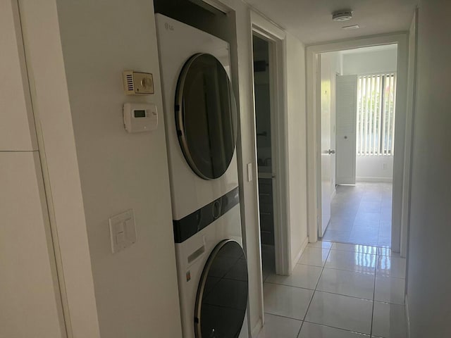 laundry area featuring laundry area, light tile patterned flooring, and stacked washer and clothes dryer