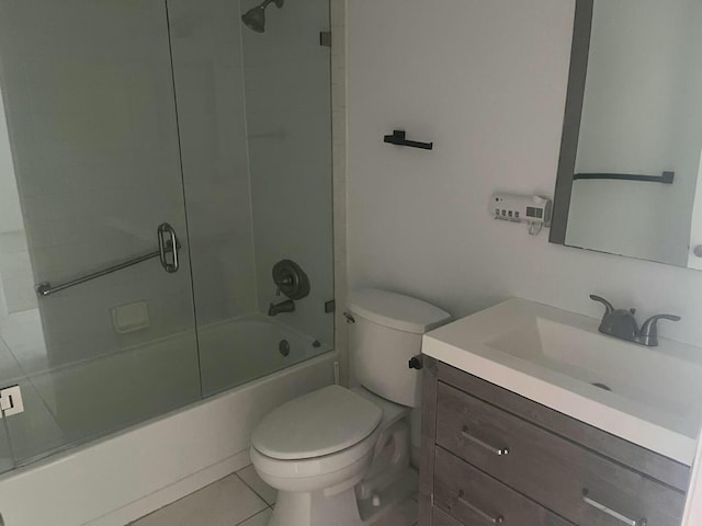 full bath with combined bath / shower with glass door, vanity, toilet, and tile patterned floors