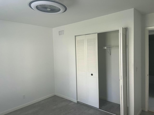 unfurnished bedroom with dark wood-type flooring, a closet, visible vents, and baseboards