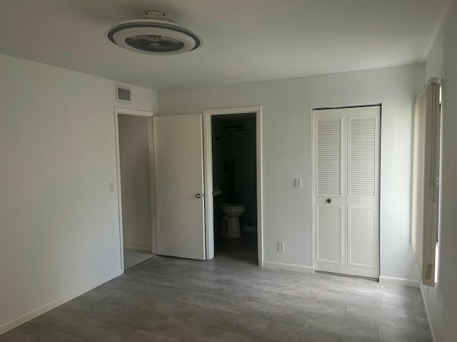 unfurnished bedroom featuring a closet, connected bathroom, visible vents, and baseboards