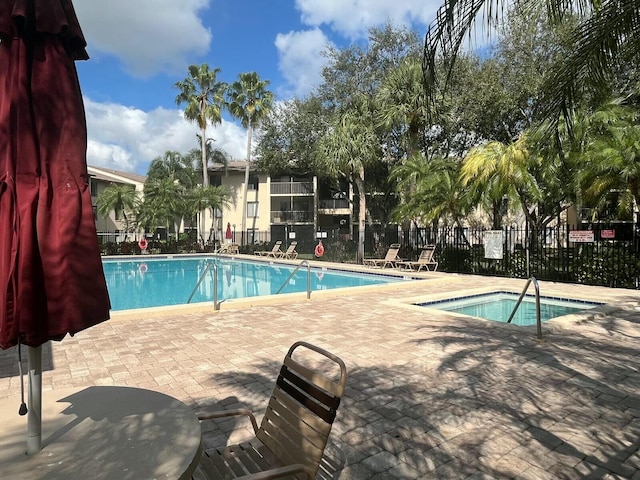 community pool with a patio area and fence