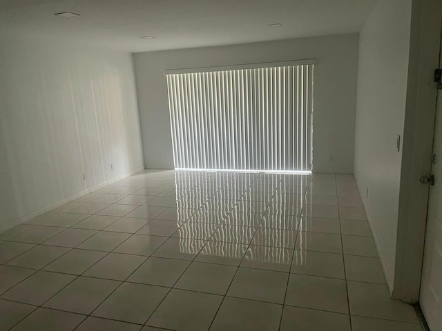 empty room featuring light tile patterned floors, plenty of natural light, and baseboards