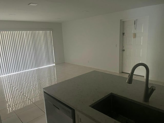 kitchen featuring dishwashing machine, light tile patterned flooring, and a sink