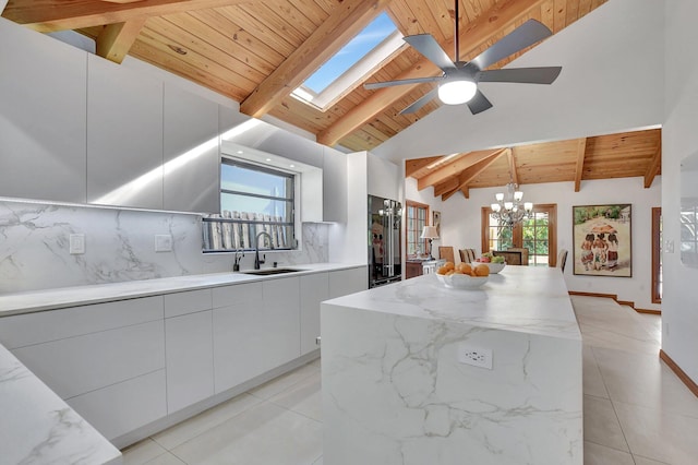 kitchen with sink, decorative backsplash, decorative light fixtures, a kitchen island, and white cabinetry