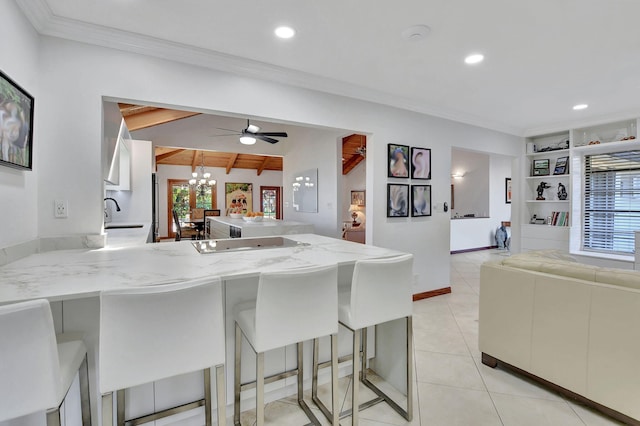 kitchen featuring a kitchen bar, kitchen peninsula, built in shelves, and lofted ceiling with beams