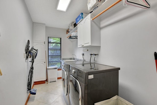 washroom featuring washing machine and clothes dryer, sink, light tile patterned flooring, and cabinets