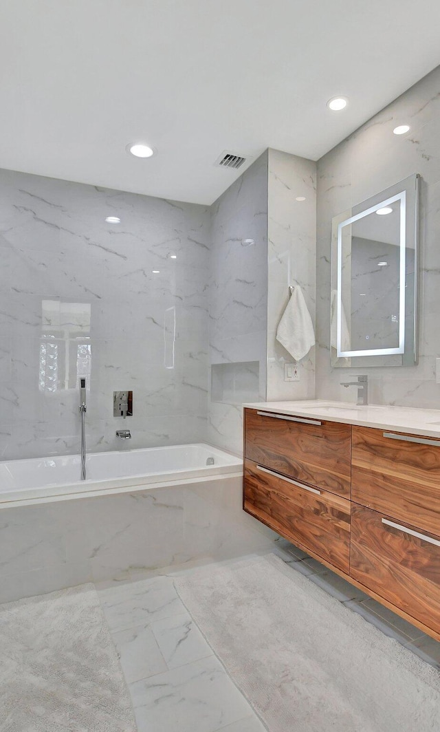 bathroom with vanity and tiled bath