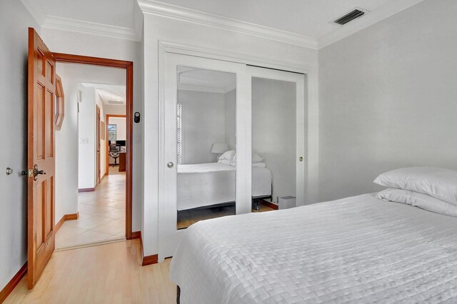 bedroom featuring a closet, light wood-type flooring, and ornamental molding