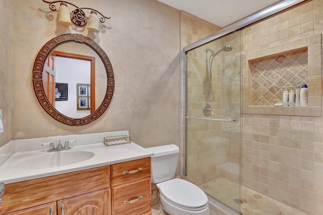 bathroom featuring vanity, toilet, and a shower with door