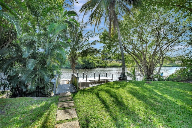 view of dock featuring a lawn and a water view