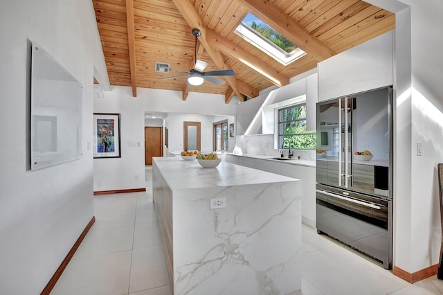 kitchen featuring a skylight, beam ceiling, a kitchen island, white cabinetry, and wood ceiling