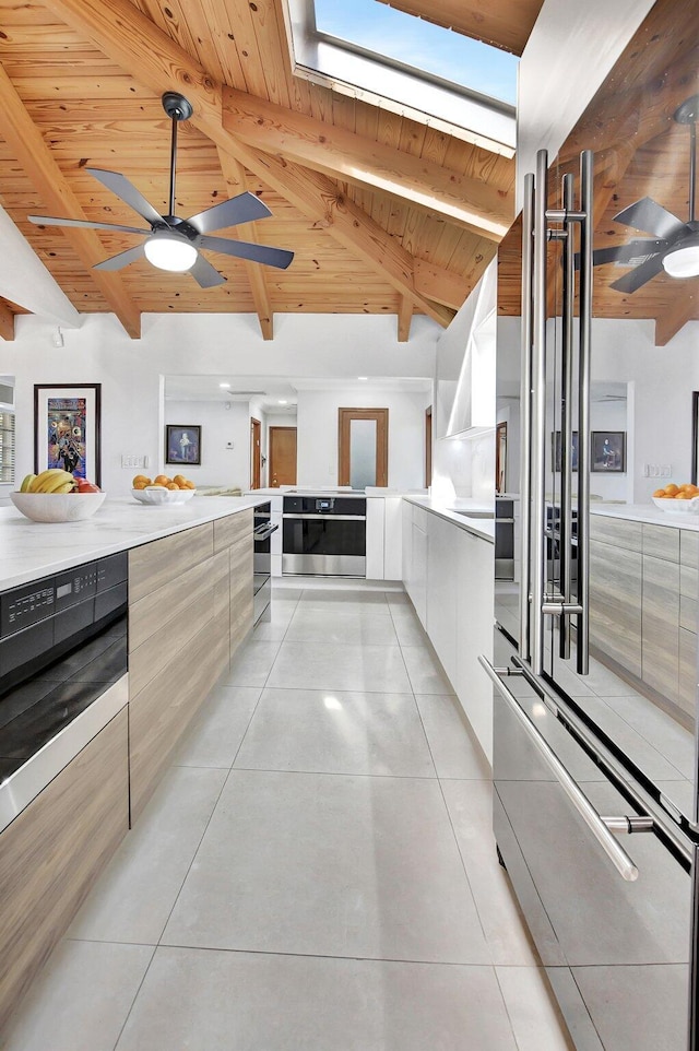 kitchen featuring a skylight, beamed ceiling, oven, white cabinets, and wood ceiling