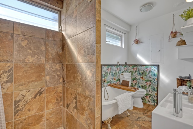 bathroom with a tub to relax in, toilet, and tile walls