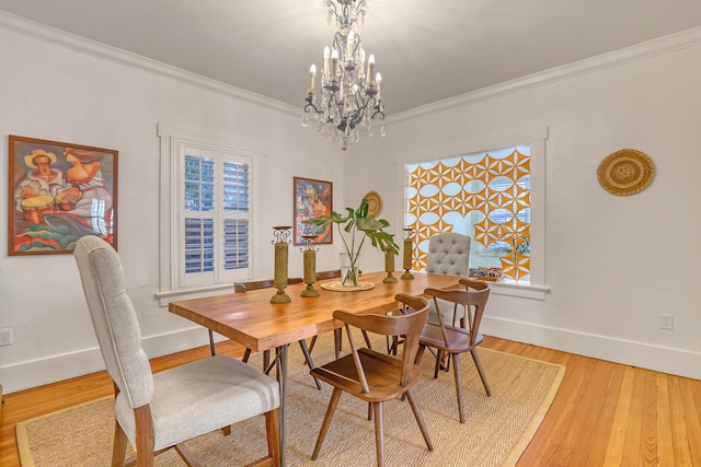 dining space featuring a healthy amount of sunlight, light wood-type flooring, ornamental molding, and a chandelier