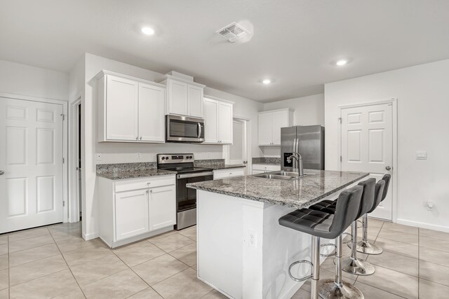 kitchen with sink, white cabinetry, a center island with sink, dark stone countertops, and appliances with stainless steel finishes