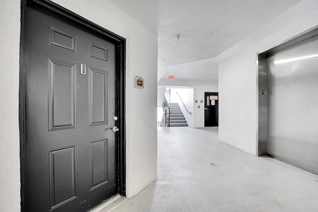 hall with a textured ceiling and elevator