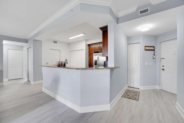 kitchen featuring kitchen peninsula, light stone countertops, ornamental molding, stainless steel fridge with ice dispenser, and light hardwood / wood-style floors