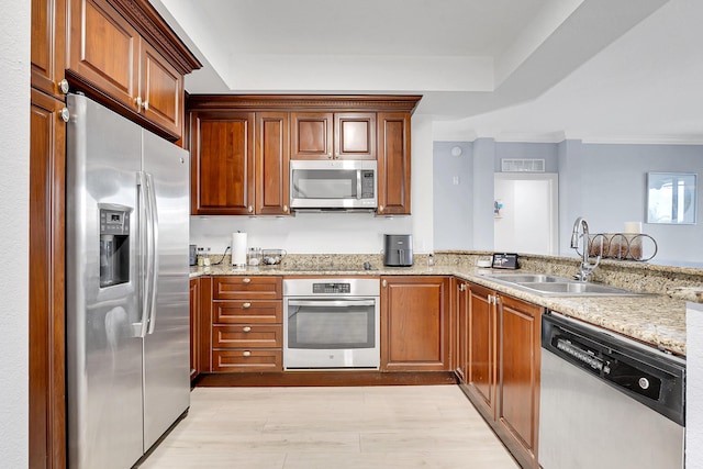 kitchen with crown molding, sink, light hardwood / wood-style flooring, light stone countertops, and stainless steel appliances