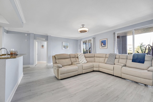 living room featuring light hardwood / wood-style floors, ornamental molding, and sink