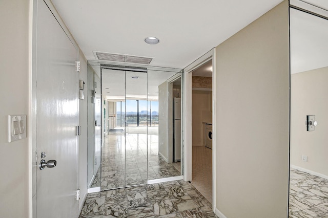 hallway with floor to ceiling windows and washer / clothes dryer