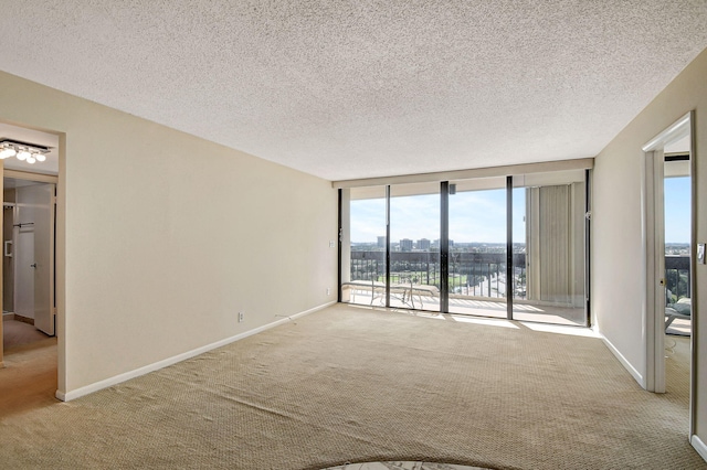 carpeted spare room with expansive windows, a water view, and a textured ceiling