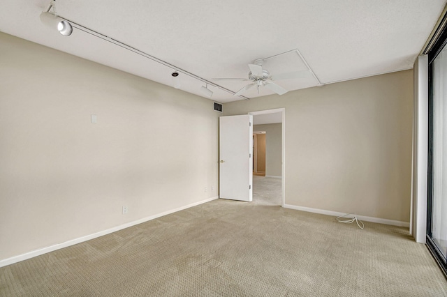 spare room featuring ceiling fan, light carpet, and track lighting