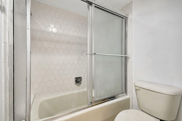 bathroom featuring toilet and bath / shower combo with glass door